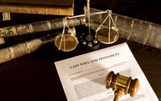 last will and testament with gavel laying on top and books and legal scale nearby