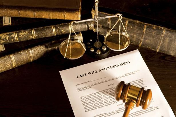 last will and testament with gavel laying on top and books and legal scale nearby