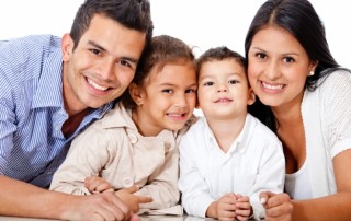 smiling family with man and woman leaning on elbows with two small children in between