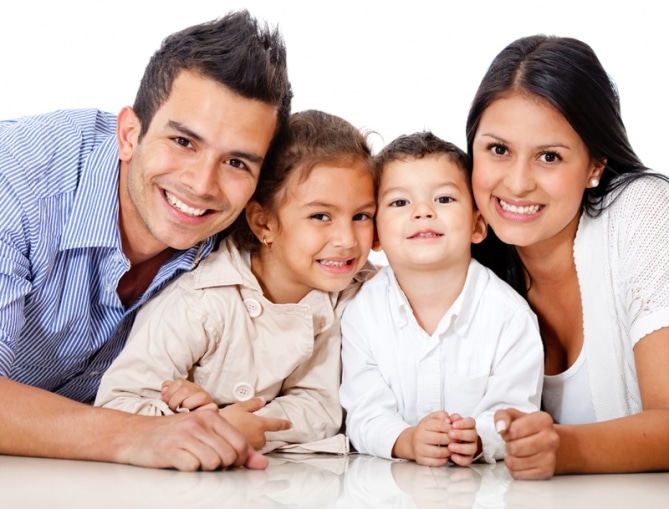 smiling family with man and woman leaning on elbows with two small children in between